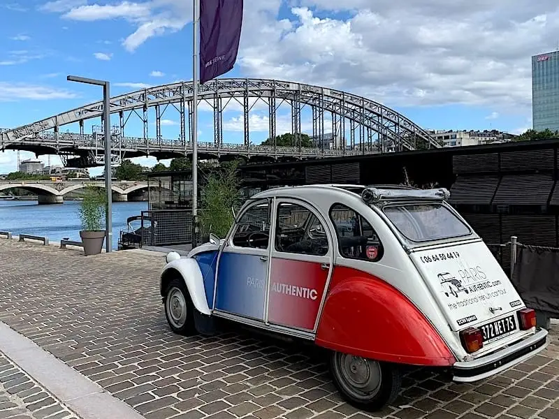 Coche 2CV azul, blanco y rojo frente al Sena