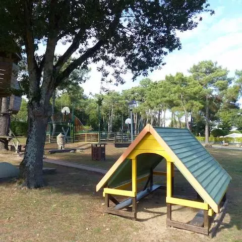 Play area with wooden cabins at Le Moulin de Kermaux Campsite