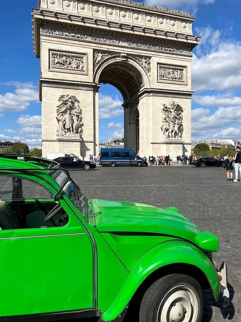 Guided tour of Paris in a 2CV Green Deux Chevaux (2CV) car in front of the Arc de Triomphe